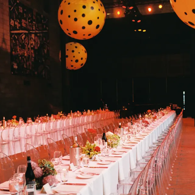 A long-table dinner under giant orange polka-dot lanterns