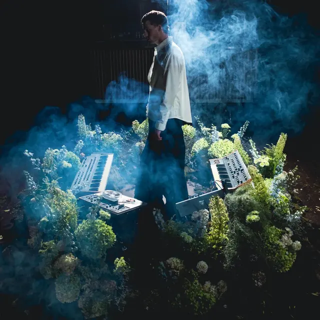 Moss and foliage installation in blue smoke with a performer