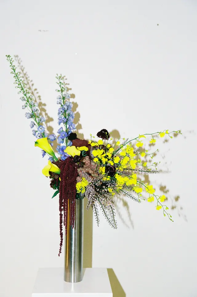 Yellow orchid and delphinium arrangement in a steel vase