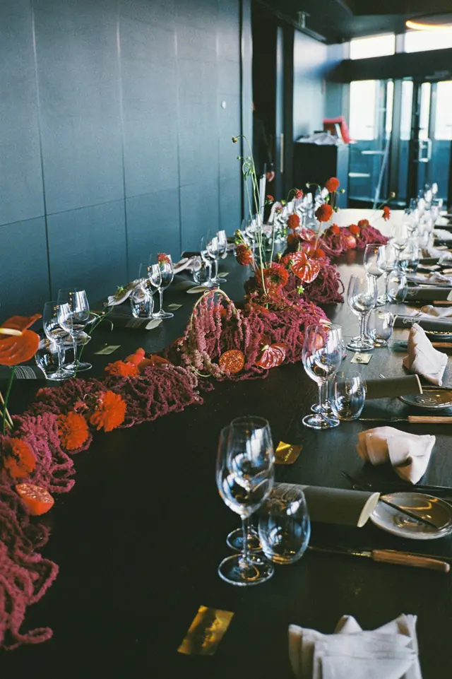 A long dinner table with a sculptural floral runner